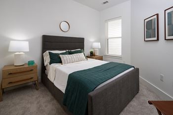 a bedroom with a bed and two nightstands and a window